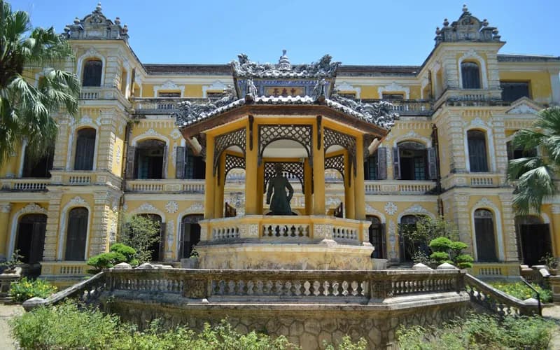 La cour intérieure d'un bâtiment colonial en pierre patiné par le temps, lumière de fin d'après-midi projetant de longues ombres sur un dallage usé