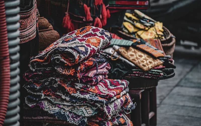 A rural market stall in a northern Vietnamese highland village, handwoven textiles and small jars of honey arranged on a wood