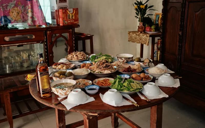 Gros plan d'une table basse en bois garnie de plusieurs petits plats en céramique de gâteaux de riz vietnamiens et de sauces d'accompagnement, intérieur chaleureux