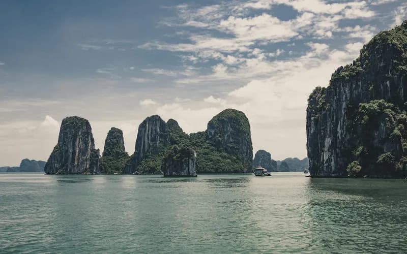Eye-level view from a kayak inside a narrow limestone karst lagoon, overhanging rock walls on both sides, still turquoise wat