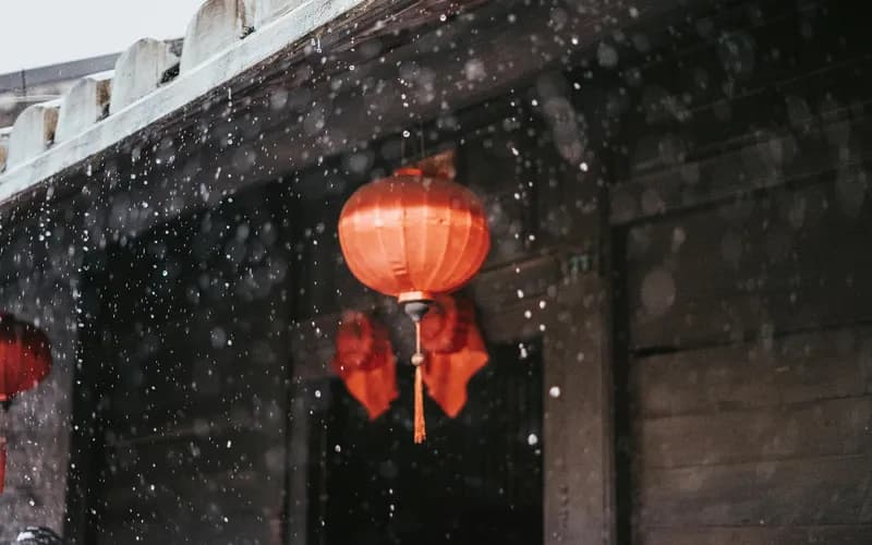 Une rue calme éclairée par des lanternes dans une ville vietnamienne historique au bord de l'eau au crépuscule, lumière dorée et chaude se reflétant sur les pavés mouillés