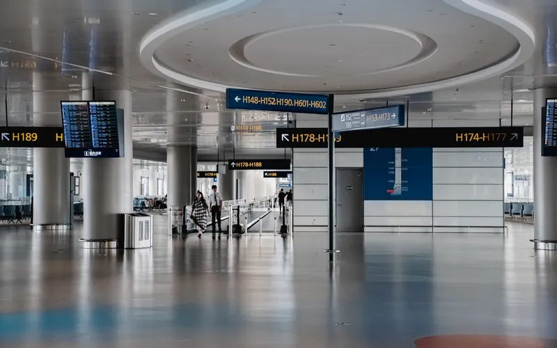 vue grand angle de l'intérieur d'un hall d'immigration, rangées de postes de contrôle des passeports, voyageurs faisant la queue dans des files organisées, éclairage froid
