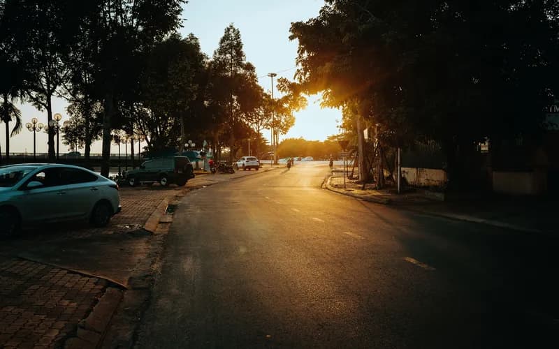a quiet Vietnamese border crossing at golden hour, low light casting warm tones across a road and checkpoint building, a few
