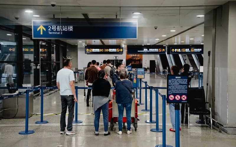 Un poste de contrôle sanitaire à l'intérieur d'un aéroport international vietnamien, un long couloir éclairé par des lumières au plafond, des voyageurs progressant vers les comptoirs