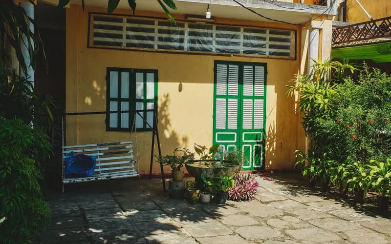 A quiet boutique hotel courtyard in central Vietnam at golden hour, warm light falling across terracotta tiles and potted tro