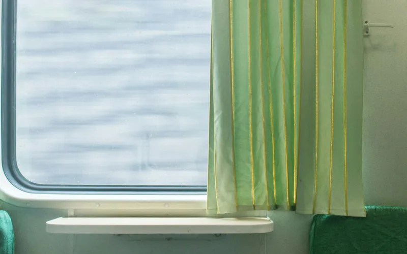 Intérieur d'un compartiment couchettes d'un train longue distance vietnamien, lumière de fin d'après-midi filtrant par la fenêtre, une tasse de thé posée sur la tablette