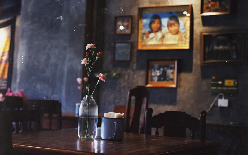 Interior of a traditional Vietnamese coffee shop in Ho Chi Minh City during a rainy afternoon, warm low lighting, rain visibl