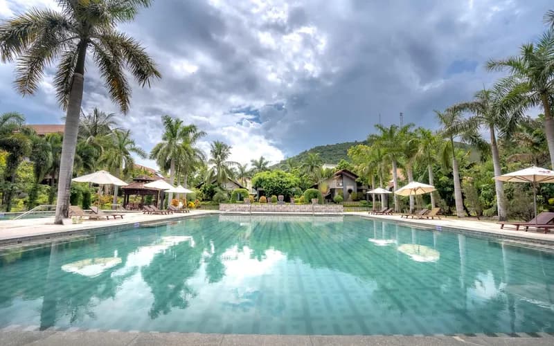 Une piscine de source thermale entourée de végétation tropicale dans le centre du Vietnam, vapeur s'élevant d'une eau riche en minéraux, lumière de fin d'après-midi