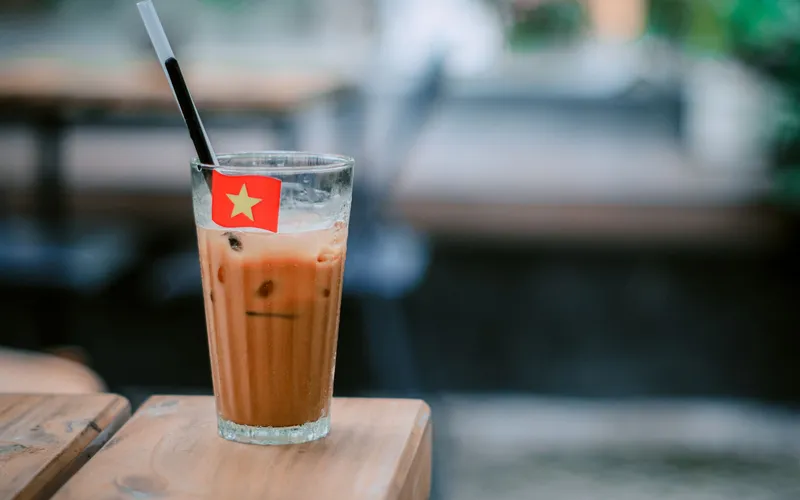 filtre phin laissant couler le café dans un verre sur une table de café
